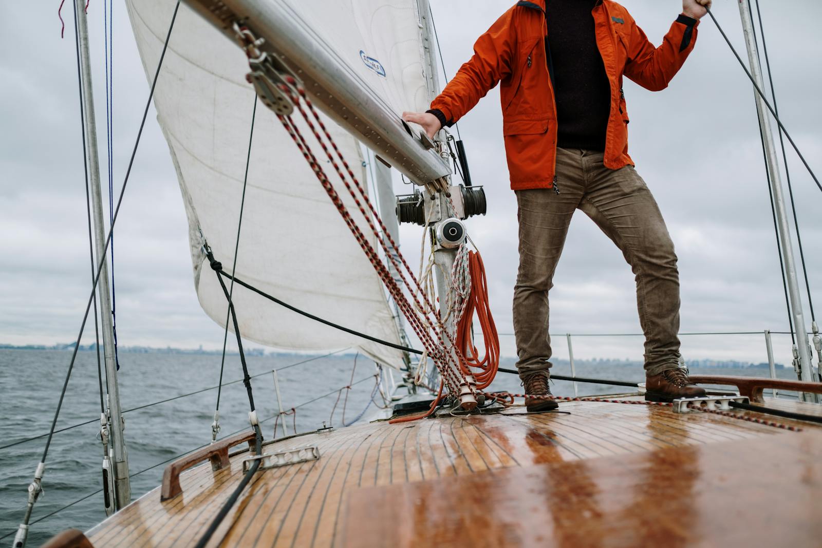 Man standing on a sailboat enjoying the journey with a vast horizon in the background.